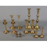 A collection of brass candlestick pairs of varying sizes to include twisted stem examples.