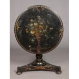 A 19th century lacquered tilt top table with painted floral and gilt decoration. Diameter of top