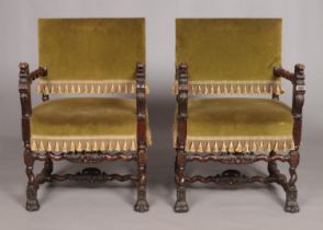 A pair of Louis XIII style carved arm chairs with velvet upholstery and carved lion mask decoration.