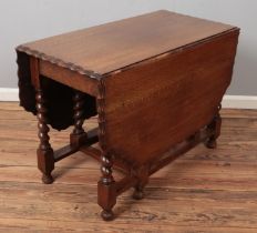 A carved oak barley twist gateleg drop leaf dining table with scalloped edge. (73cm x 106cm x