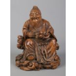 A Chinese carved bamboo figure formed as Dongfang Shuo seated in robes and holding a peach of