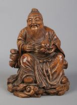 A Chinese carved bamboo figure formed as Dongfang Shuo seated in robes and holding a peach of