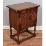 A carved oak Old Charm style side cabinet raised on turned support. (68cm x 51cm).