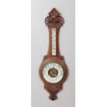 A carved oak banjo aneroid wall barometer. Cracks to central dial. Mercury present.