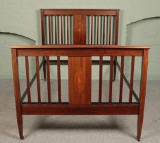 An Edwardian mahogany double bed, with iron supports, inlay panel detailing and banding to head