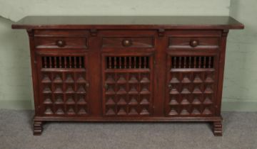 A large hardwood sideboard, with drawer top and lower cupboard doors. Features spindle and paneled