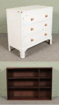 A white painted three drawer chest along with an oak open bookcase.