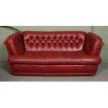 A red leather, deep button cushion Chesterfield style three piece suite. Comprising of a large