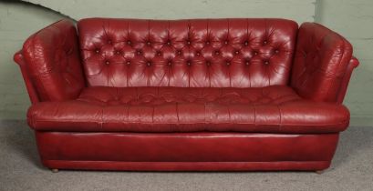 A red leather, deep button cushion Chesterfield style three piece suite. Comprising of a large