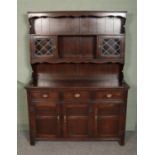 A Jaycee carved oak dresser, with glazed doors to the top and cupboard and drawer base featuring