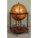 A Globe drinks cabinet, with turned oak supports, hinged top, horoscopic border and rotating base.
