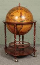 A Globe drinks cabinet, with turned oak supports, hinged top, horoscopic border and rotating base.