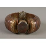 A large copper hinged bangle with yellow metal mounts and set with a polished hardstone.