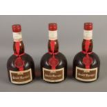 Three full and sealed bottles of Grand Marnier orange and cognac liqueur.