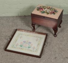 A small sewing box/footstool with contents of sewing accessories along with embroidery mounted as