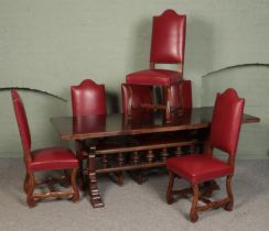 A large dark oak dining table, with spindle stretcher base, together with a set of six studded red