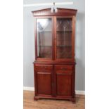 A hardwood glazed display cabinet raised on drawer and cupboard base with lockable doors. Keys are