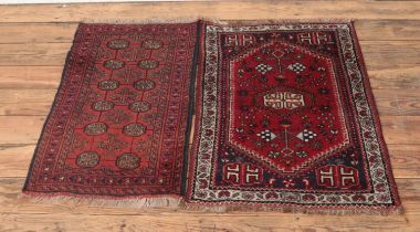 Two small red ground wool rugs featuring fringed edges and floral pattern detail. Approx. length