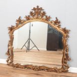 A large, gilt framed ornate mirror, with curved top and floral decoration. Height: 117cm, Width: