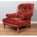 A Howard style deep button back armchair, with scrolled arms, red upholstery and turned front