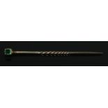 A Gold and Emerald stick pin, with part twisted stem. 47mm long. Size of stone 3mm. Total weight: