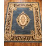 A large blue ground machine knotted wool rug, with cream and dark blue border and central floral