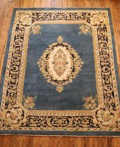 A large blue ground machine knotted wool rug, with cream and dark blue border and central floral