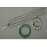Three pieces of jade jewellery. Includes bead necklace with pendant, bead bracelet and bangle.