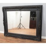 A large moulded composite bevel edged wall mirror. Height: 130cm, Width: 157cm.
