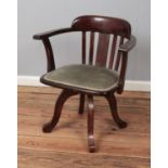 An oak captains swivel chair featuring upholstered seat and slat back support.