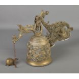 An ornate brass wall hanging bell with chain decorated with floral motifs and cherubs.