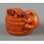 A Japanese carved Netsuke in the form of a turtle and a frog in a barrel.