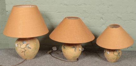 Three graduated ceramic table lamps with floral decoration. Tallest example (61cm)