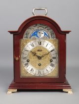 A Hermle mahogany effect bracket clock, raised on brass paw feet. With silvered dial on brass