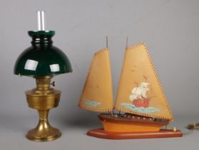 A brass oil lamp featuring green glass shade along with novelty lamp formed as a boat.