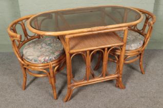 A glass top conservatory table and two chairs. Approx. table size 110cm x 56cm.