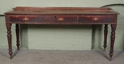 A large Victorian stool height railroad station desk with turned legs and cup handle drawers.
