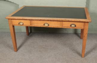 A large leather top oak writing desk with three drawers and brass cup handles. Hx77cm Wx153cm Dx92cm