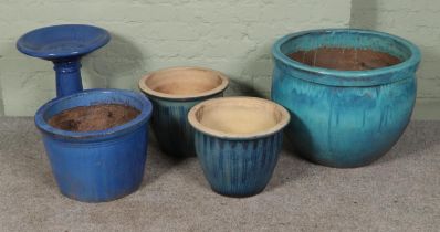 A collection of blue glazed garden planters along with small blue glazed birdbath.