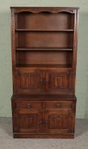 A carved oak bookcase with lower cupboard featuring linen fold decoration. Approx. dimensions 95cm x