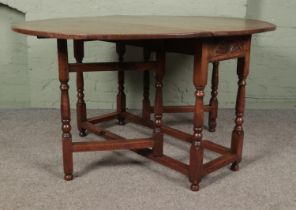 An oak drop leaf gate leg table featuring carved sun burst motif to ends. Approx. dimensions with