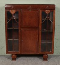 An oak side by side bureau with glazed front, drop down door and carved decoration. Height: 125cm,