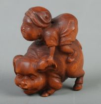 A Japanese carved Netsuke in the form of a boy riding a pig