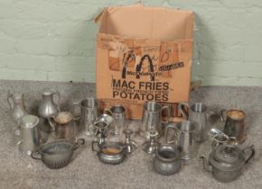 A box of metalwares. Includes teapot, ewers, tankards, twin handle bowls, etc.