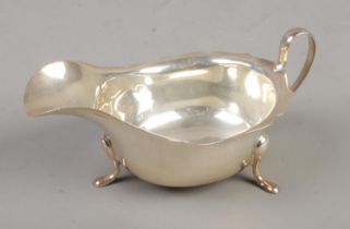 A George V silver sauce boat raised on three scrolled feet. Assayed Sheffield 1935 by Viner's. 108g.