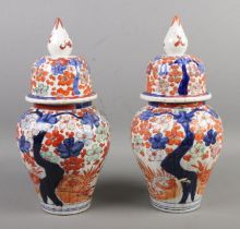 A pair of Chinese lidded vases, decorated with Prunus blossom in blues and oranges, with pointed