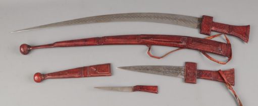 An early 20th century tribal sword having a clad tooled leather handle of traditional form, steel
