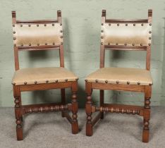 A pair of Oak Old Charm dining chairs, model 2313. With spindle front stretcher and studded seat pad