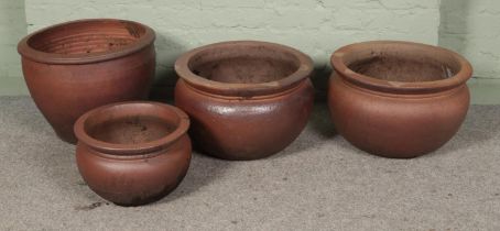 Four matching terracotta planters of varying sizes.