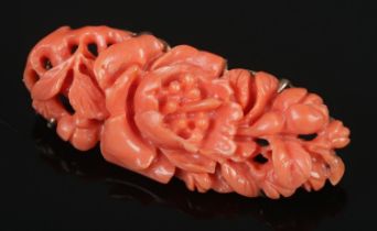 An ornately carved unmarked coral brooch featuring floral design.
